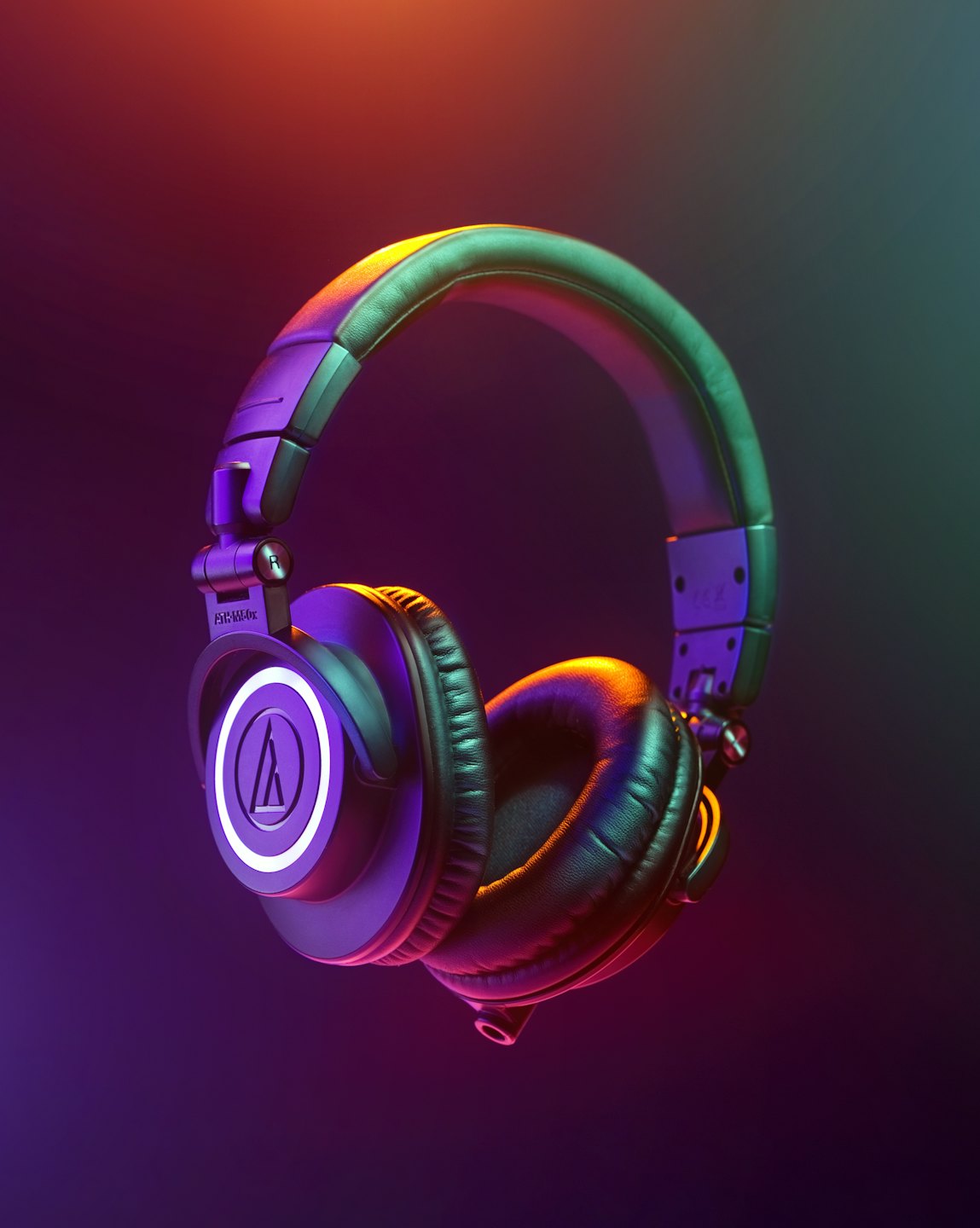 Black over-ear headphones floating against a dark colorful background.
