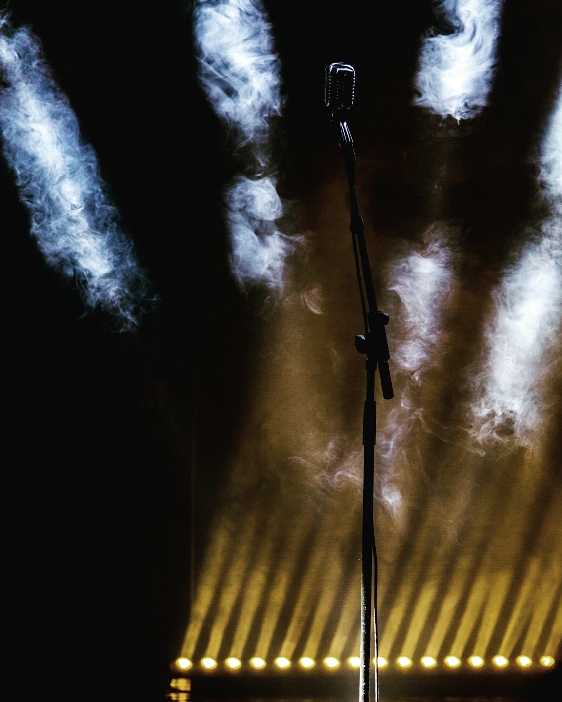 A vintage silver microphone stands on a black boom stand.
