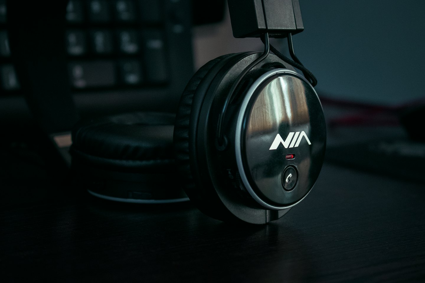 Black over-ear headphones sitting on a wooden desk.