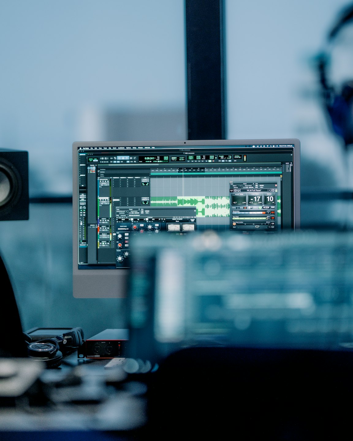 Computer screen shows audio software waveforms and controls.
