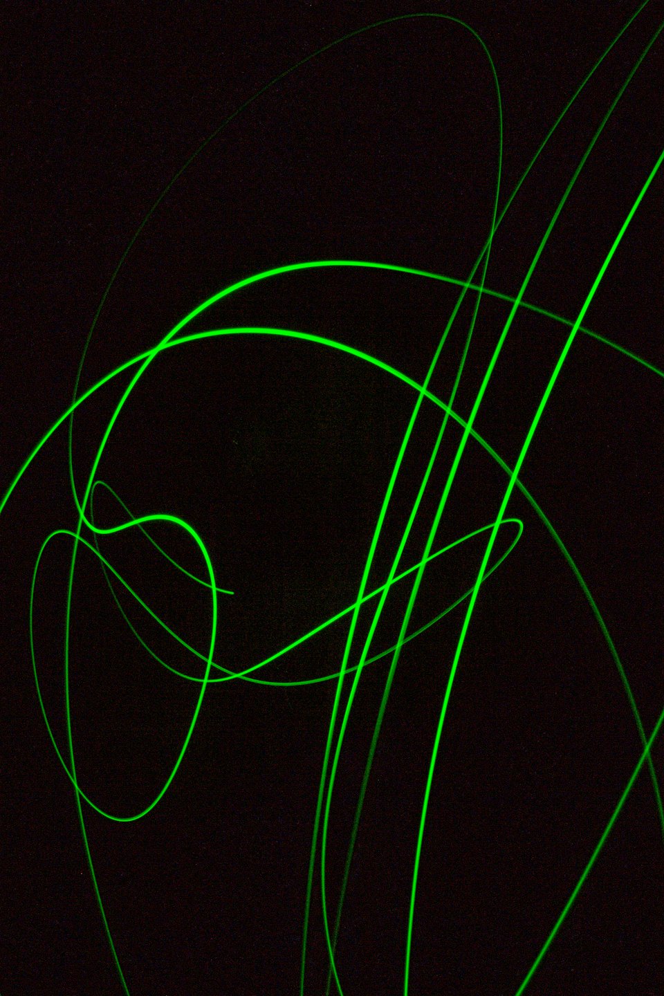 Neon green light trails curve and crisscross on a dark background.