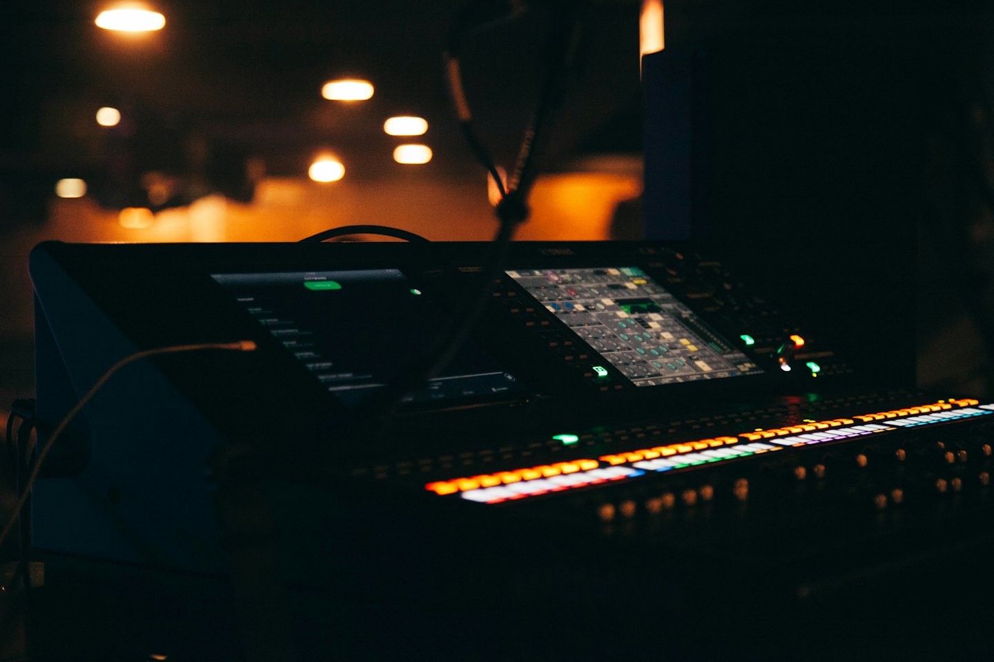 Digital audio mixing console with glowing buttons and screens.